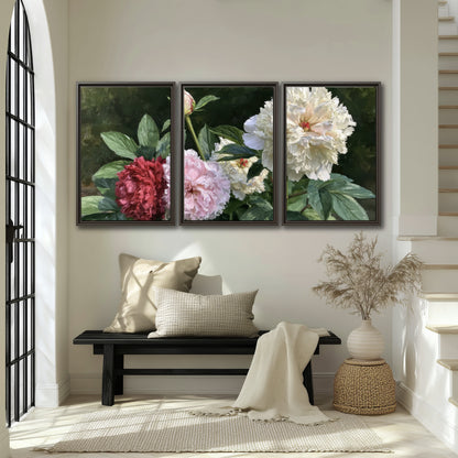 Cream, blush and red peonies surrounded by fresh green leaves 3 piece framed canvas wall art displayed in a entryway