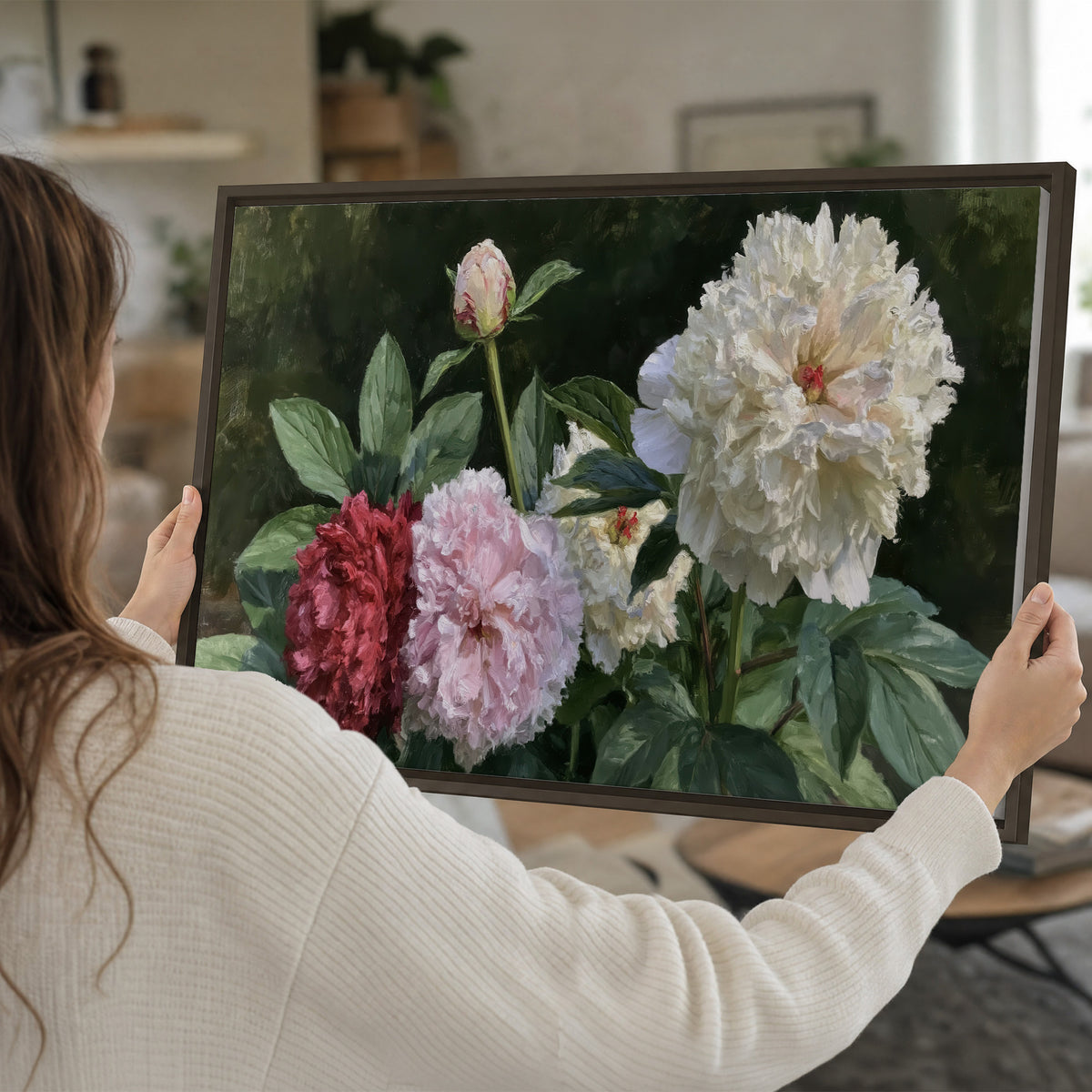Cream, blush and red peonies surrounded by fresh green leaves single framed canvas wall art held in hands
