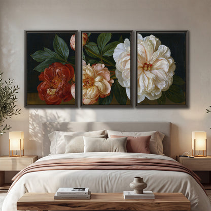 A large pale peony beside small ruby-red and peach flowers on a deep green ground 3 piece framed canvas wall art displayed in a bedroom