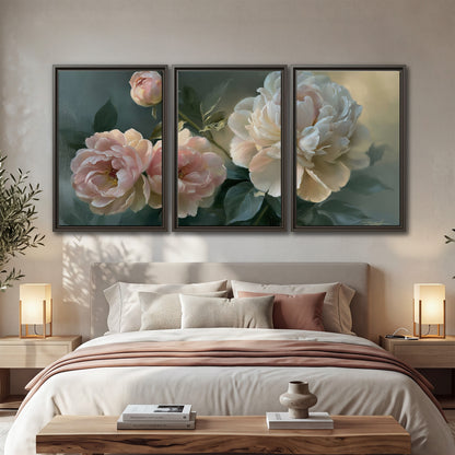 A large cream peony beside blush flowers and broad green leaves 3 piece framed canvas wall art displayed in a bedroom