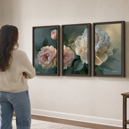 A large cream peony beside blush flowers and broad green leaves 3 piece framed canvas wall art three panel arrangement on a wall