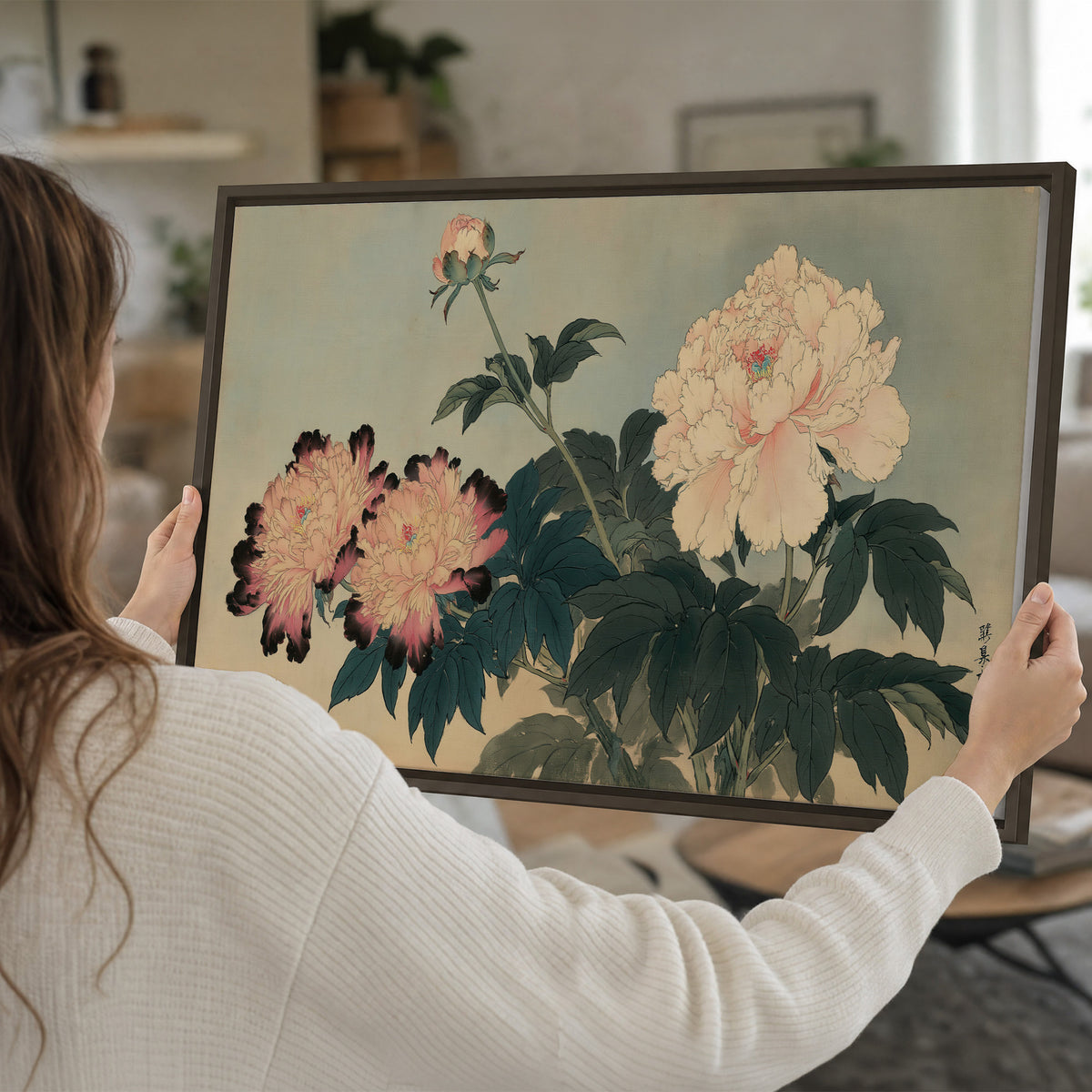 Pink and cream peonies with dark green leaves on a warm beige ground single framed canvas wall art held in hands