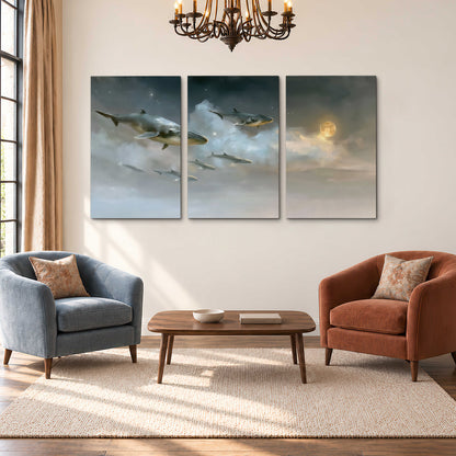 Whales drifting through pale dreamlike clouds toward a golden moon 3 piece canvas wall art styled in an interior