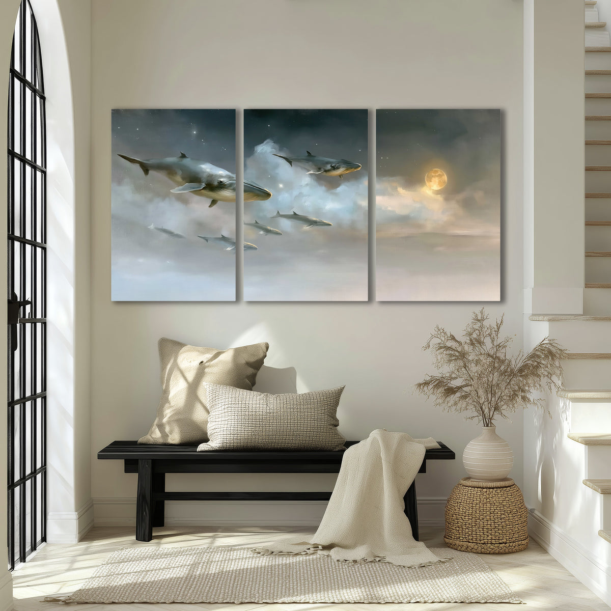 Whales drifting through pale dreamlike clouds toward a golden moon 3 piece canvas wall art displayed in a entryway