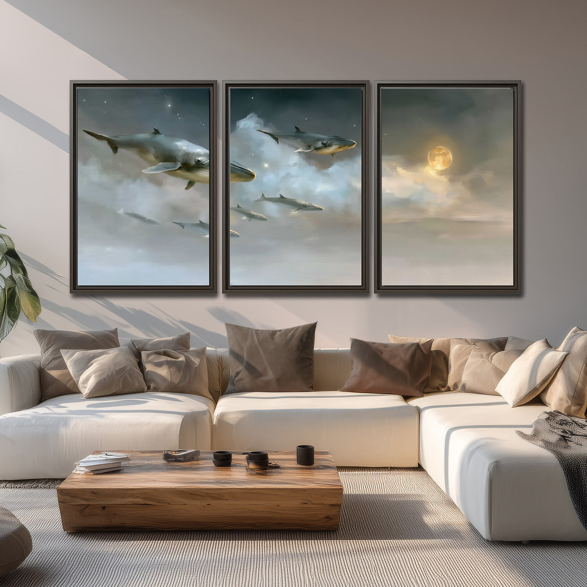 Whales drifting through pale dreamlike clouds toward a golden moon 3 piece framed canvas wall art displayed in a living room