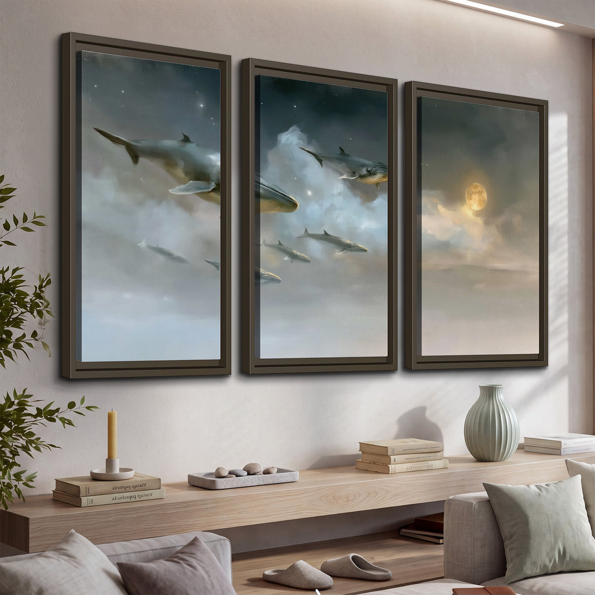 Whales drifting through pale dreamlike clouds toward a golden moon 3 piece framed canvas wall art displayed in a console
