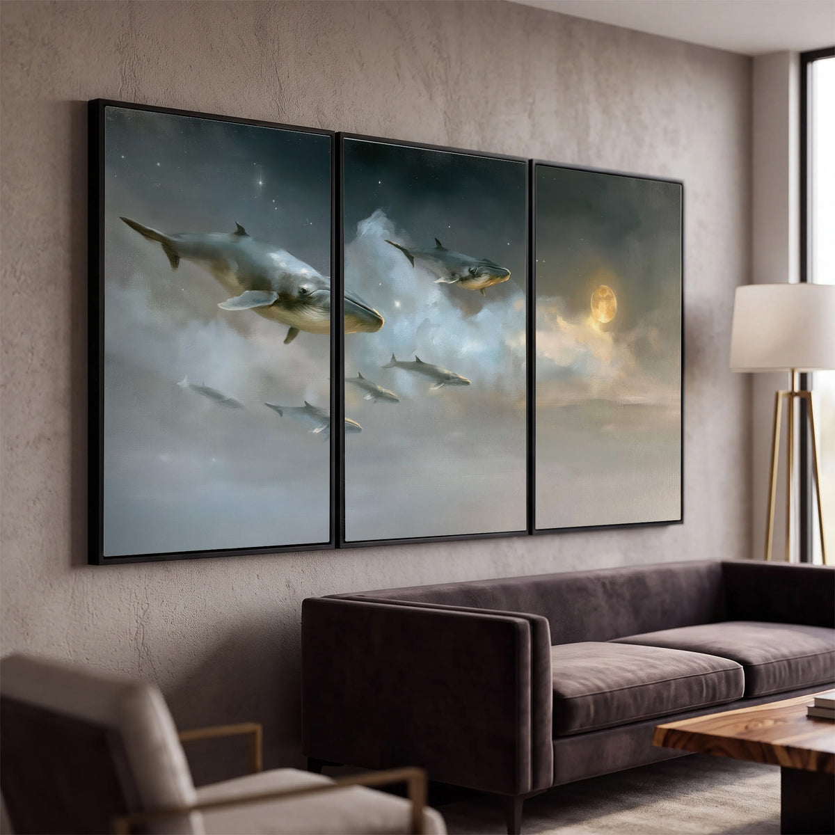Whales drifting through pale dreamlike clouds toward a golden moon 3 piece framed canvas wall art displayed in a modern living room