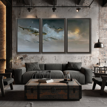 Whales drifting through pale dreamlike clouds toward a golden moon 3 piece framed canvas wall art displayed in a industrial room
