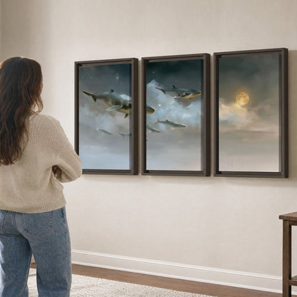 Whales drifting through pale dreamlike clouds toward a golden moon 3 piece framed canvas wall art three panel arrangement on a wall