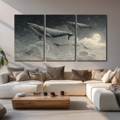Monochrome whales floating over misty clouds beside a luminous painted moon 3 piece canvas wall art displayed in a living room