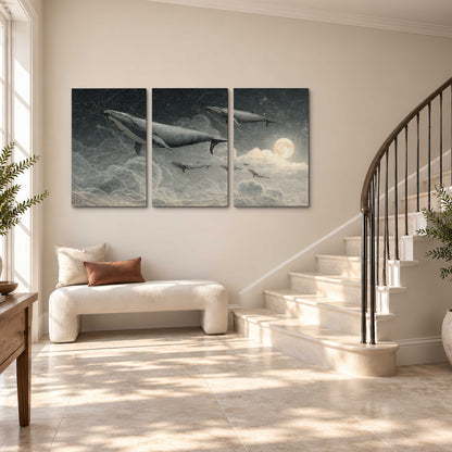Monochrome whales floating over misty clouds beside a luminous painted moon 3 piece canvas wall art styled in an interior