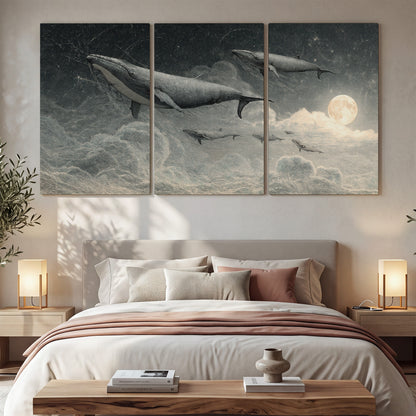 Monochrome whales floating over misty clouds beside a luminous painted moon 3 piece canvas wall art displayed in a bedroom