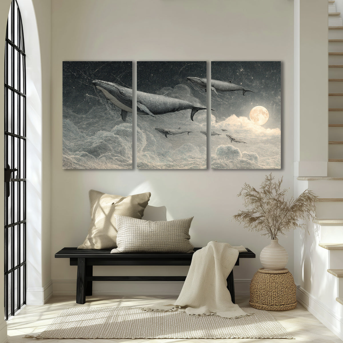 Monochrome whales floating over misty clouds beside a luminous painted moon 3 piece canvas wall art displayed in a entryway