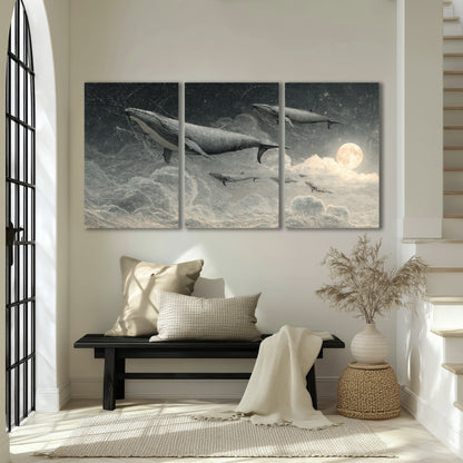 Monochrome whales floating over misty clouds beside a luminous painted moon 3 piece canvas wall art displayed in a entryway