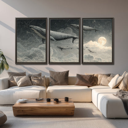 Monochrome whales floating over misty clouds beside a luminous painted moon 3 piece framed canvas wall art displayed in a living room