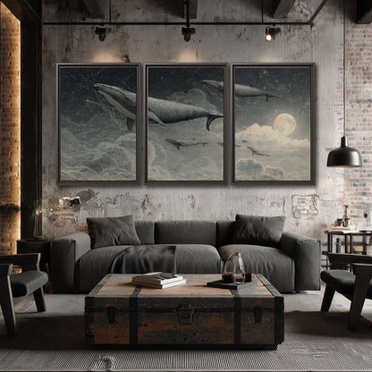 Monochrome whales floating over misty clouds beside a luminous painted moon 3 piece framed canvas wall art displayed in a industrial room