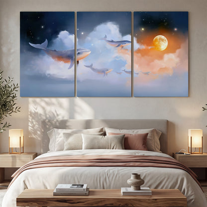 Blue whales gliding through pastel clouds beneath stars and a warm orange moon 3 piece canvas wall art displayed in a bedroom
