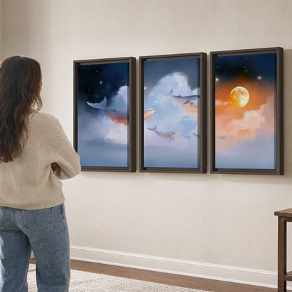 Blue whales gliding through pastel clouds beneath stars and a warm orange moon 3 piece framed canvas wall art three panel arrangement on a wall