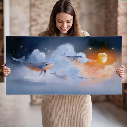 Blue whales gliding through pastel clouds beneath stars and a warm orange moon single canvas wall art held in hands