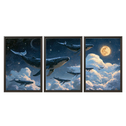 A group of whales floating among clouds beneath a golden moon in a deep blue night sky 3 piece framed canvas wall art viewed straight on