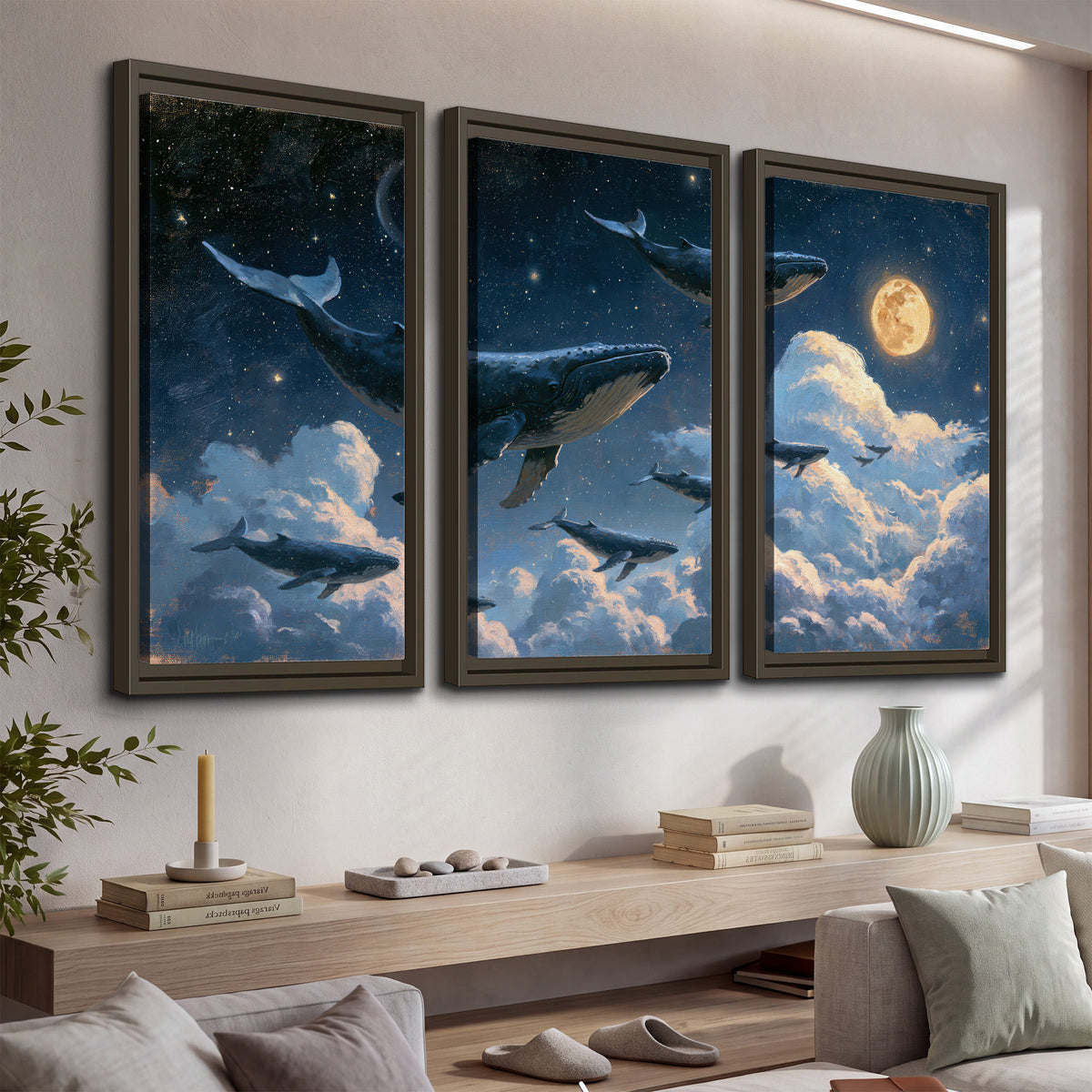 A group of whales floating among clouds beneath a golden moon in a deep blue night sky 3 piece framed canvas wall art displayed in a console