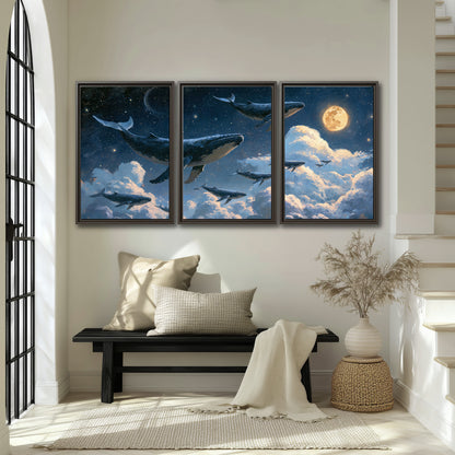 A group of whales floating among clouds beneath a golden moon in a deep blue night sky 3 piece framed canvas wall art displayed in a entryway