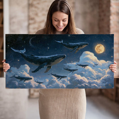 A group of whales floating among clouds beneath a golden moon in a deep blue night sky single canvas wall art held in hands