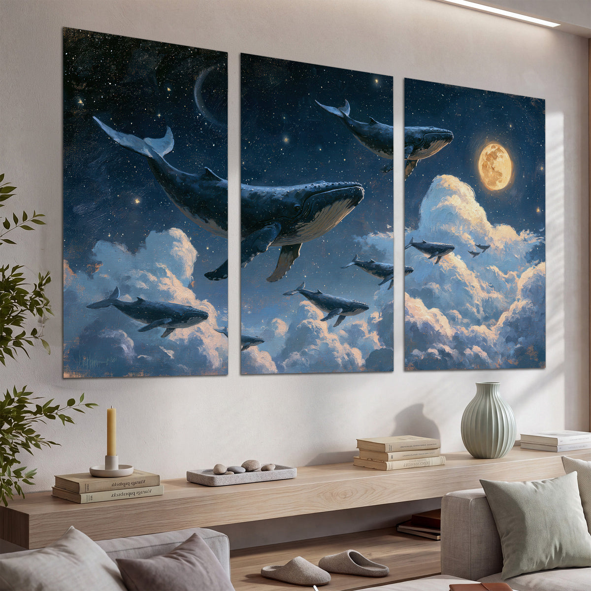 A group of whales floating among clouds beneath a golden moon in a deep blue night sky set of 3 poster prints displayed in a console