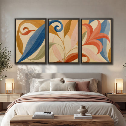 Bold blue, coral and golden leaf-like shapes flowing across a cream ground 3 piece framed canvas wall art displayed in a bedroom