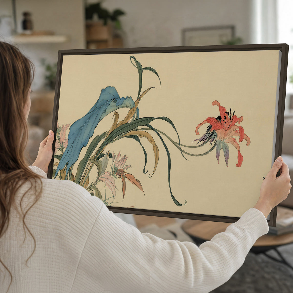 A delicate red flower and long blue-green leaves on a warm cream ground single framed canvas wall art held in hands