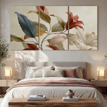 Cream flowers with broad blue and rust leaves sweeping across a neutral background 3 piece canvas wall art displayed in a bedroom