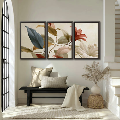 Cream flowers with broad blue and rust leaves sweeping across a neutral background 3 piece framed canvas wall art displayed in a entryway