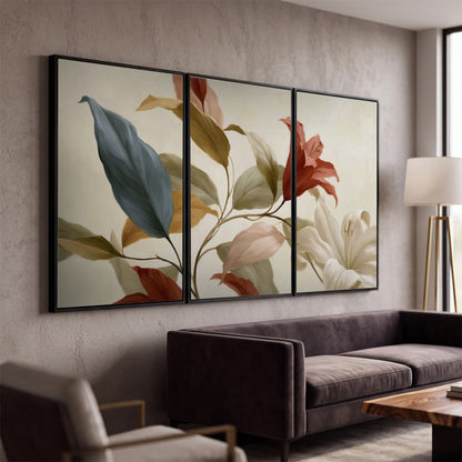 Cream flowers with broad blue and rust leaves sweeping across a neutral background 3 piece framed canvas wall art displayed in a modern living room