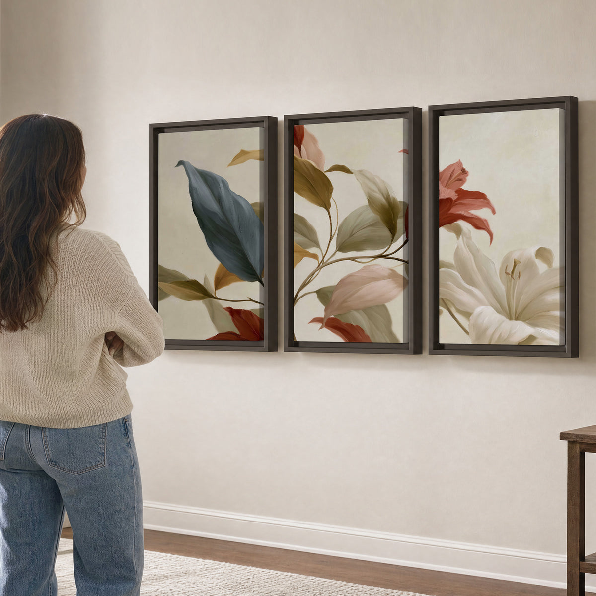 Cream flowers with broad blue and rust leaves sweeping across a neutral background 3 piece framed canvas wall art three panel arrangement on a wall