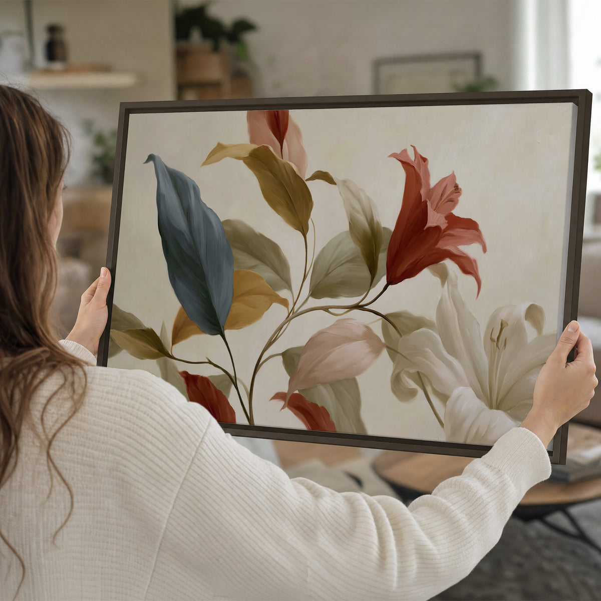 Cream flowers with broad blue and rust leaves sweeping across a neutral background single framed canvas wall art held in hands