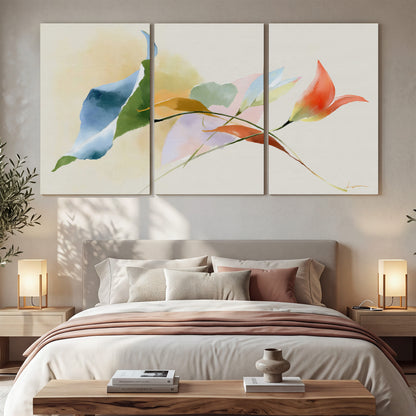 Airy green, orange and blue organic shapes floating across a white background 3 piece canvas wall art displayed in a bedroom