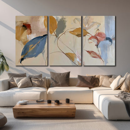 Loose ochre, blue and pink leaves arranged on a pale layered background 3 piece canvas wall art displayed in a living room