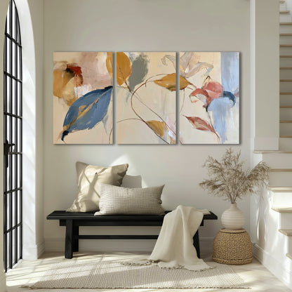 Loose ochre, blue and pink leaves arranged on a pale layered background 3 piece canvas wall art displayed in a entryway