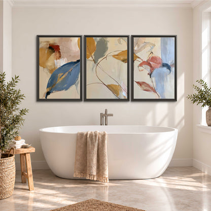 Loose ochre, blue and pink leaves arranged on a pale layered background 3 piece framed canvas wall art styled in an interior