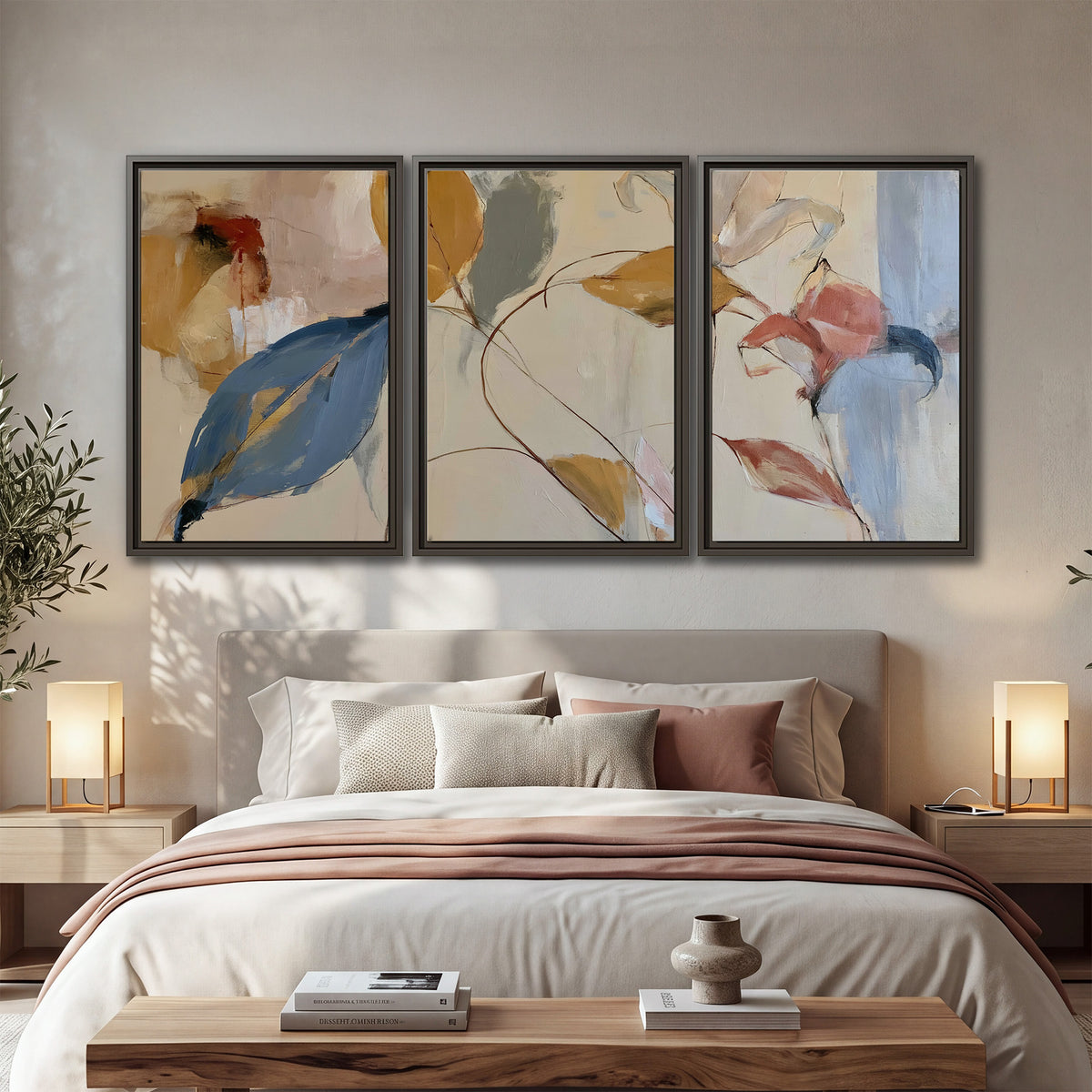 Loose ochre, blue and pink leaves arranged on a pale layered background 3 piece framed canvas wall art displayed in a bedroom