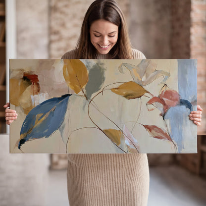 Loose ochre, blue and pink leaves arranged on a pale layered background single canvas wall art held in hands