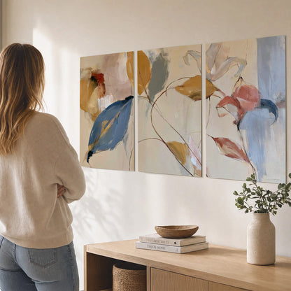 Loose ochre, blue and pink leaves arranged on a pale layered background set of 3 poster prints three panel arrangement on a wall