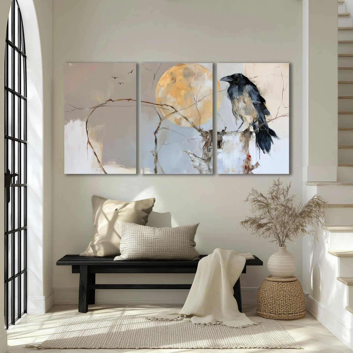 A dark raven beside a golden moon amid pale blue and cream painterly strokes 3 piece canvas wall art displayed in a entryway