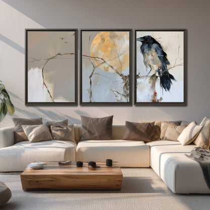 A dark raven beside a golden moon amid pale blue and cream painterly strokes 3 piece framed canvas wall art displayed in a living room