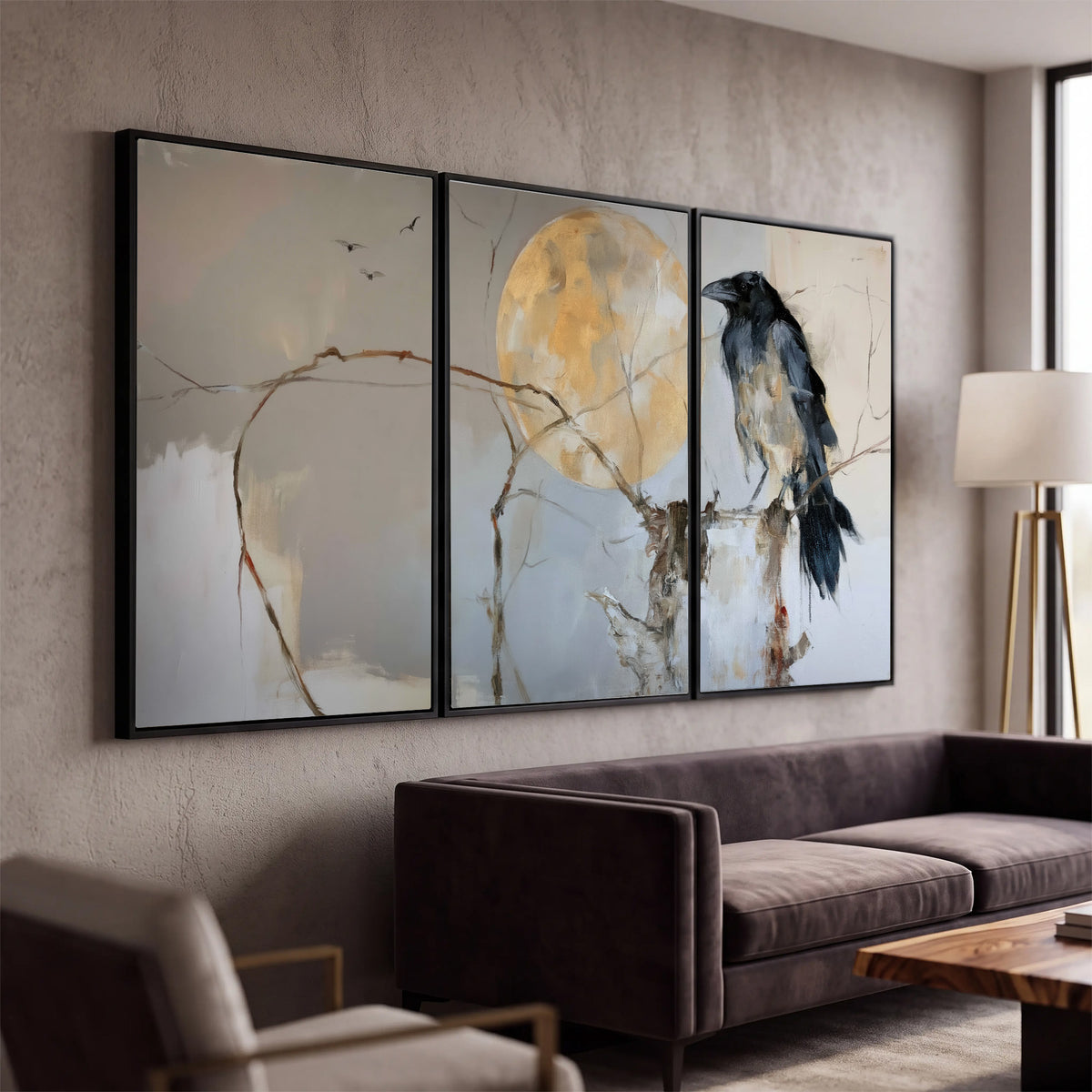 A dark raven beside a golden moon amid pale blue and cream painterly strokes 3 piece framed canvas wall art displayed in a modern living room
