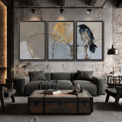 A dark raven beside a golden moon amid pale blue and cream painterly strokes 3 piece framed canvas wall art displayed in a industrial room