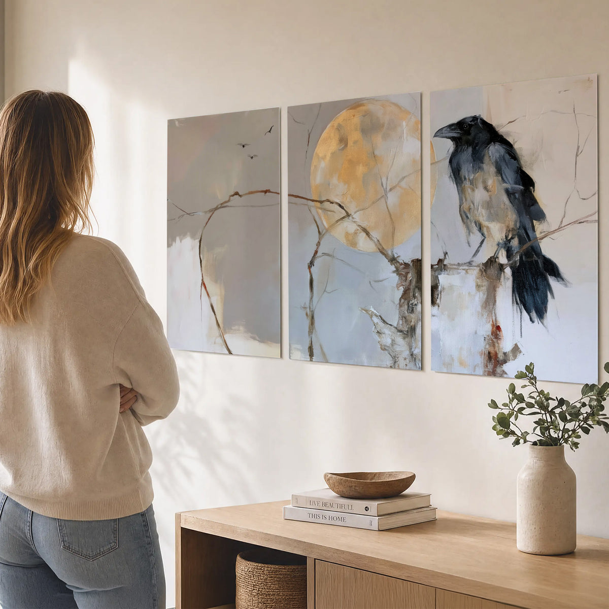 A dark raven beside a golden moon amid pale blue and cream painterly strokes set of 3 poster prints three panel arrangement on a wall