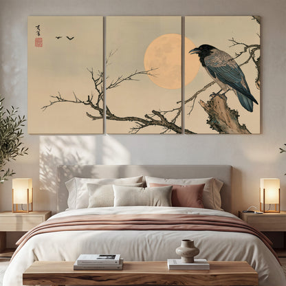 A dark raven perched on a bare branch beside a warm full moon 3 piece canvas wall art displayed in a bedroom