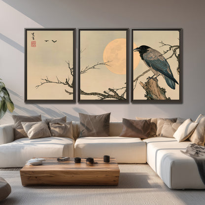 A dark raven perched on a bare branch beside a warm full moon 3 piece framed canvas wall art displayed in a living room