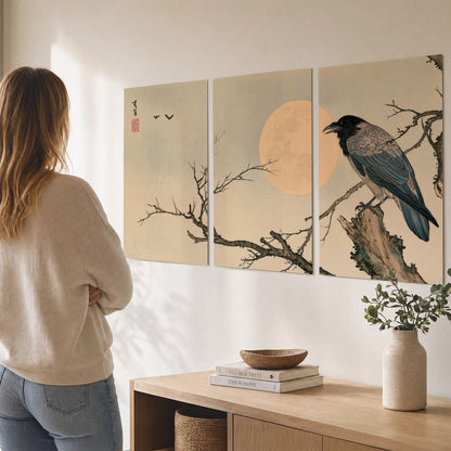 A dark raven perched on a bare branch beside a warm full moon set of 3 poster prints three panel arrangement on a wall